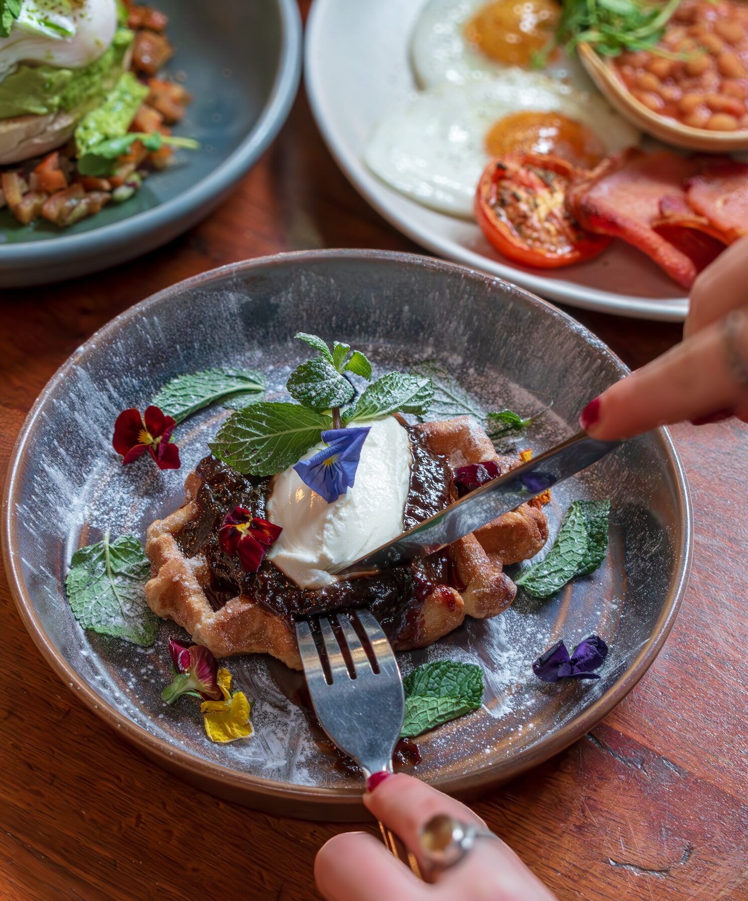 A close-up of a decadent waffle dish at Racks Bar & Kitchen, adorned with fresh cream, berries, and edible flowers. Paired with a rich brunch selection and the option of bottomless Prosecco or Bloody Marys, this image highlights why Racks is renowned for the best bottomless brunch in Bristol.